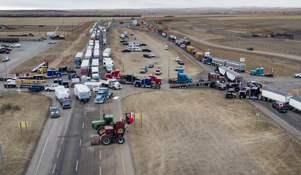 A truck convoy protesting COVID-19 rules, including a vaccine mandate for truckers, blocks the highway at the busy U.S. border crossing in Coutts, Alta., on Monday, Jan. 31, 2022.