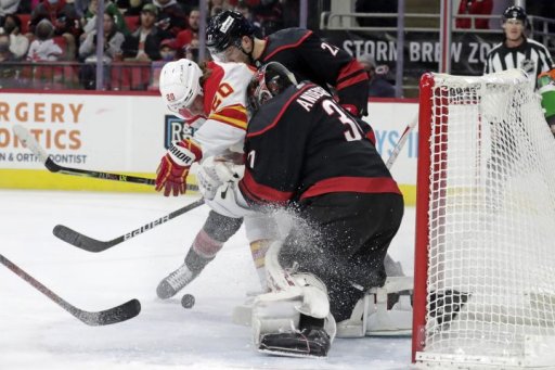Calgary Flames forward Blake Coleman, left, fights for the puck against Carolina Hurricanes defenceman Brett Pesce, top centre, and goaltender Frederik Andersen (31) during the first period of an NHL hockey game Friday, Jan. 7, 2022, in Raleigh, N.C.