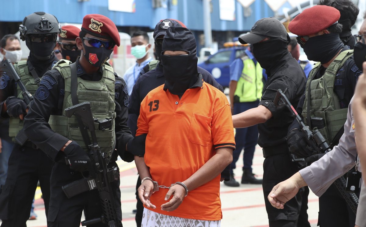 Police officers escort suspected militant Zulkarnaen, center, who is also known as Aris Sumarsono, upon arrival at Soekarno-Hatta International Airport in Tangerang, Indonesia, Wednesday, Dec. 16, 2020. Indonesian authorities have transferred suspected militants arrested in recent weeks to the country’s capital, including Zulkarnaen, a bomb maker and the architect of a series of deadly attacks and sectarian conflicts in the world’s largest Muslim majority nation.(AP Photo/Achmad Ibrahim).