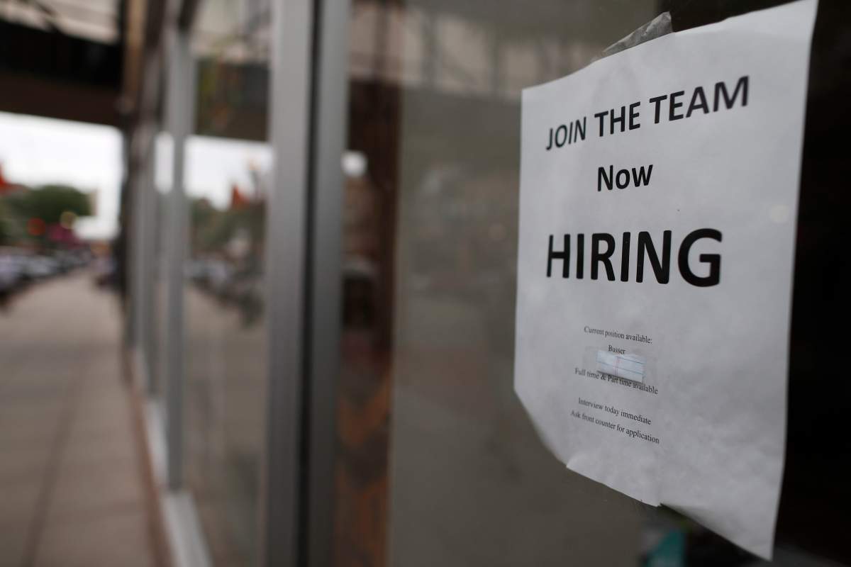 A sign that says "Now Hiring" posted on a small business.