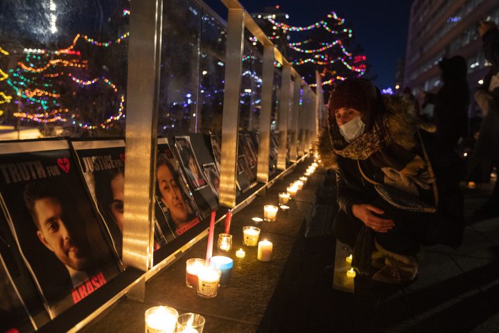 A mourner looks at the faces of the victims, during a memorial for the anniversary of flight PS752 in Edmonton on Friday, January 8, 2021. 