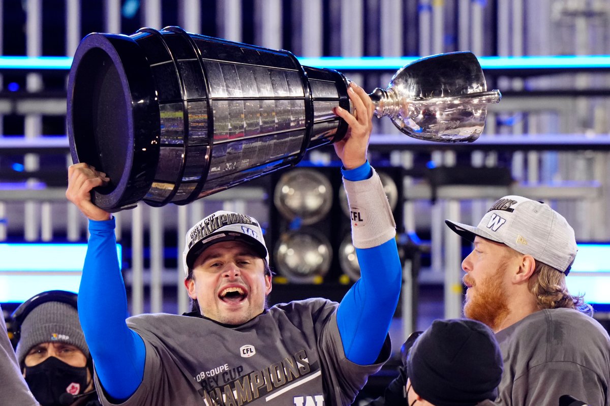 Winnipeg Blue Bombers quarterback Zach Collaros (8) hoists the Grey Cup as he celebrates defeating the Hamilton Tiger-Cats in the 108th CFL Grey Cup in Hamilton, Ont., on Sunday, December 12, 2021. 