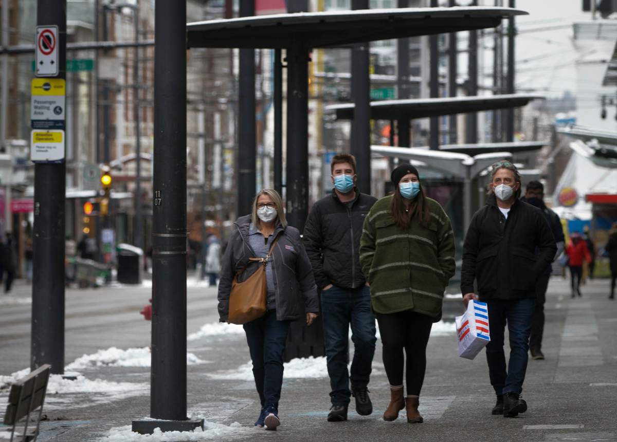 People wearing face masks walk on a street in Vancouver, British Columbia, Canada, on Dec. 27, 2021