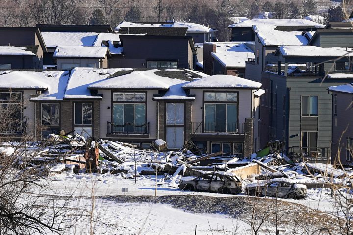 Snow covers the burned remains of homes after wildfires ravaged the area Sunday, Jan.2, 2022, in Superior, Colo.