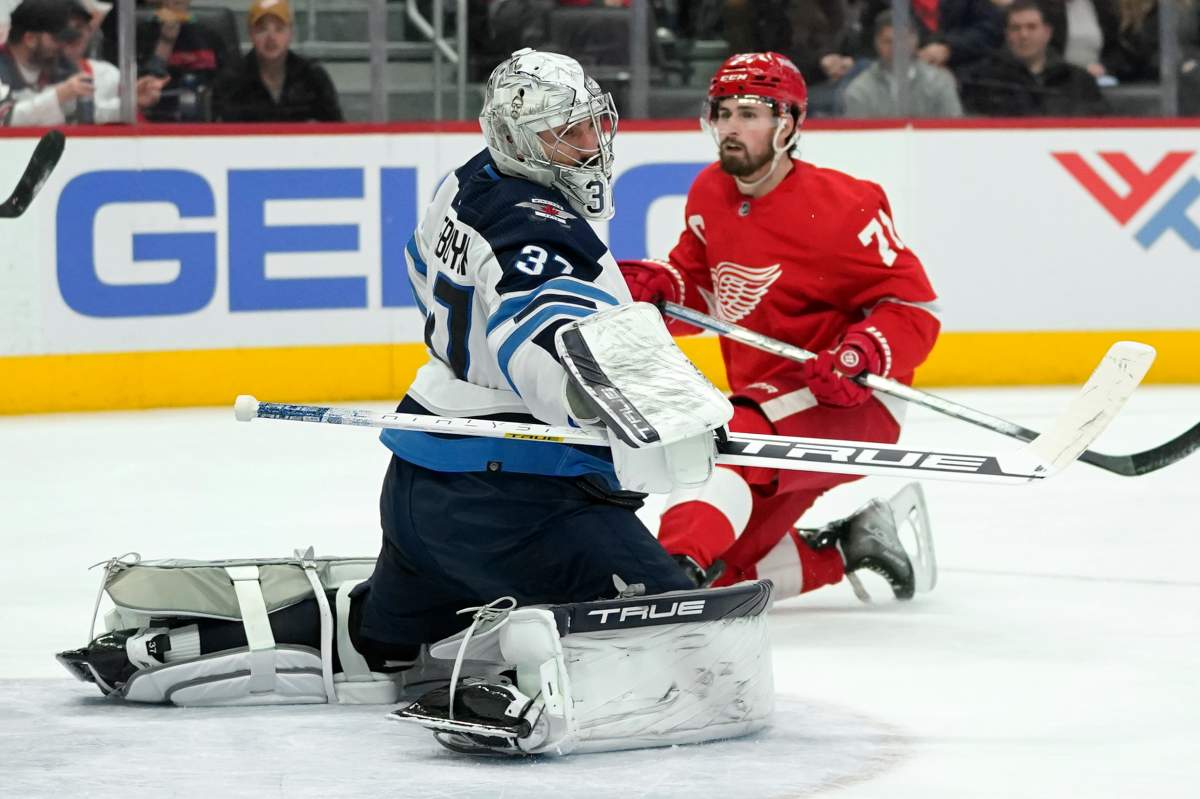 Winnipeg Jets goaltender Connor Hellebuyck (37) deflects a Detroit Red Wings center Dylan Larkin (71) shot in the second period of an NHL hockey game Thursday, Jan. 13, 2022, in Detroit. (AP Photo/Paul Sancya)