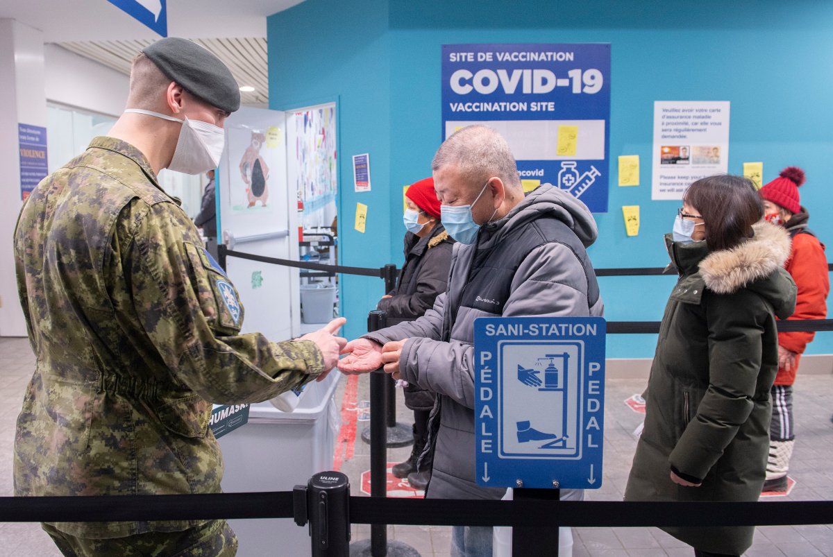 A member of the Canadian Armed Forces dispenses hand sanitizer at a COVID-19 vaccination site in Montreal, Sunday, January 16, 2022, as the COVID-19 pandemic continues in Canada. 