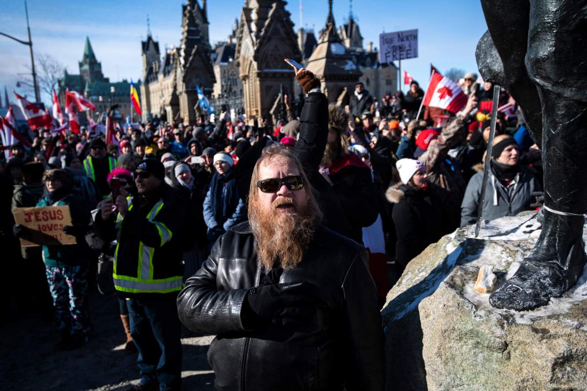 A person holds their hand to their heart during a singing of O Canada during a rally against COVID-19 restrictions on Parliament Hill, which began as a cross-country convoy protesting a federal vaccine mandate for truckers, in Ottawa on Sunday, Jan. 30, 2022. THE CANADIAN PRESS/Justin Tang