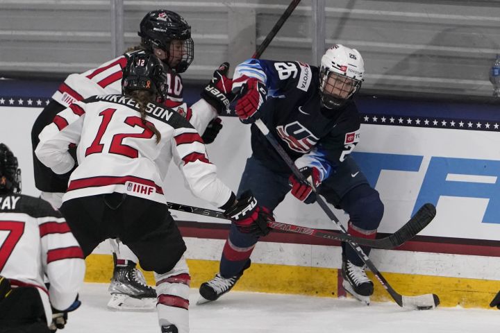 FILE - United States' Kendall Coyne Schofield (26) looks to pass as Canada's Meaghan Mikkelson (12) defends during the first period of a women's exhibition hockey game ahead of the Beijing Olympics Wednesday, Dec. 15, 2021, in Maryland Heights, Mo. 