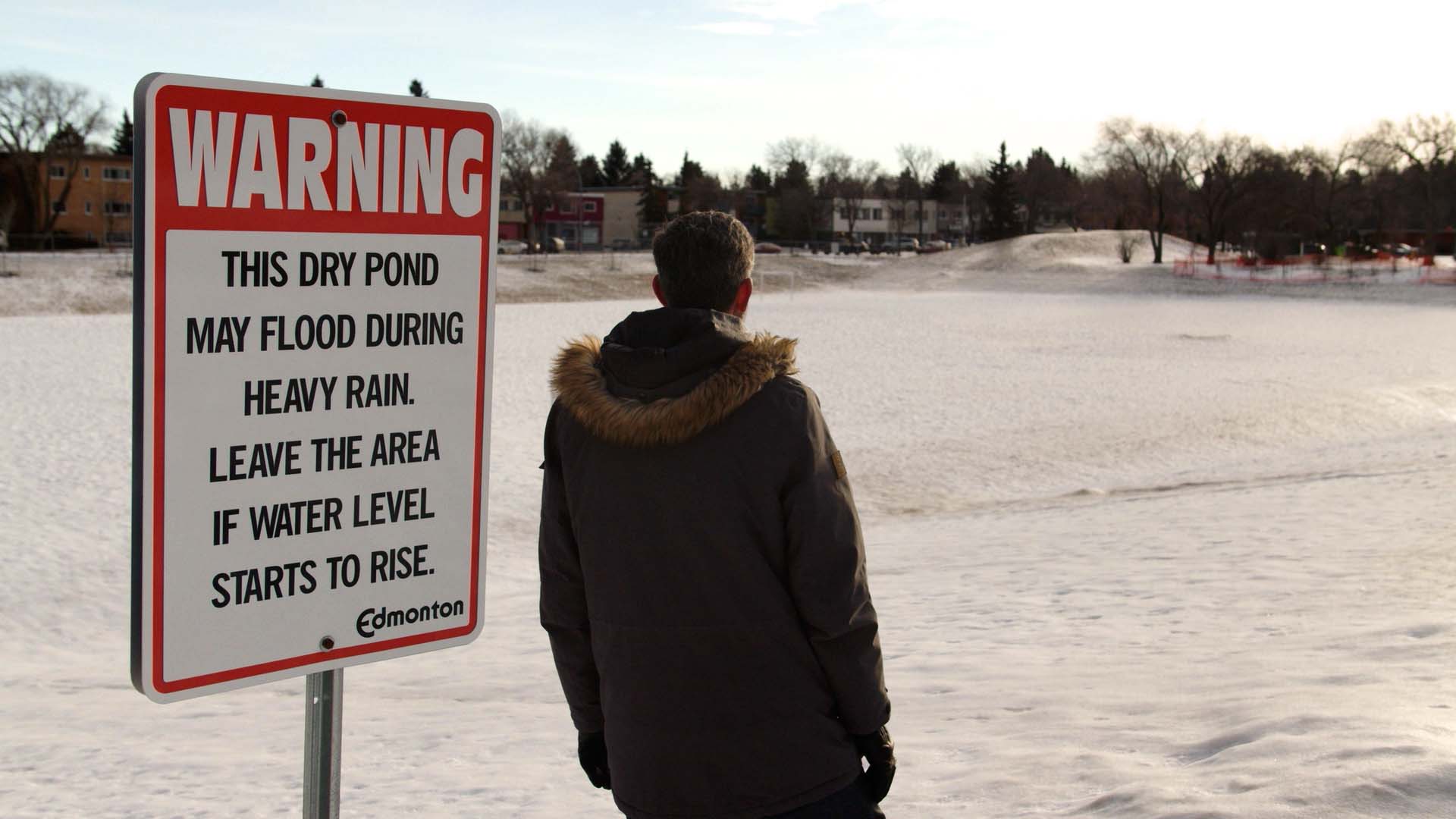 Don Iveson looks out over the dry pond in Parkallen, Alta. It will divert and store water in the event of the flood. “You’ll see from the slope of the ground here that there’s quite a big bathtub,” Iveson says.