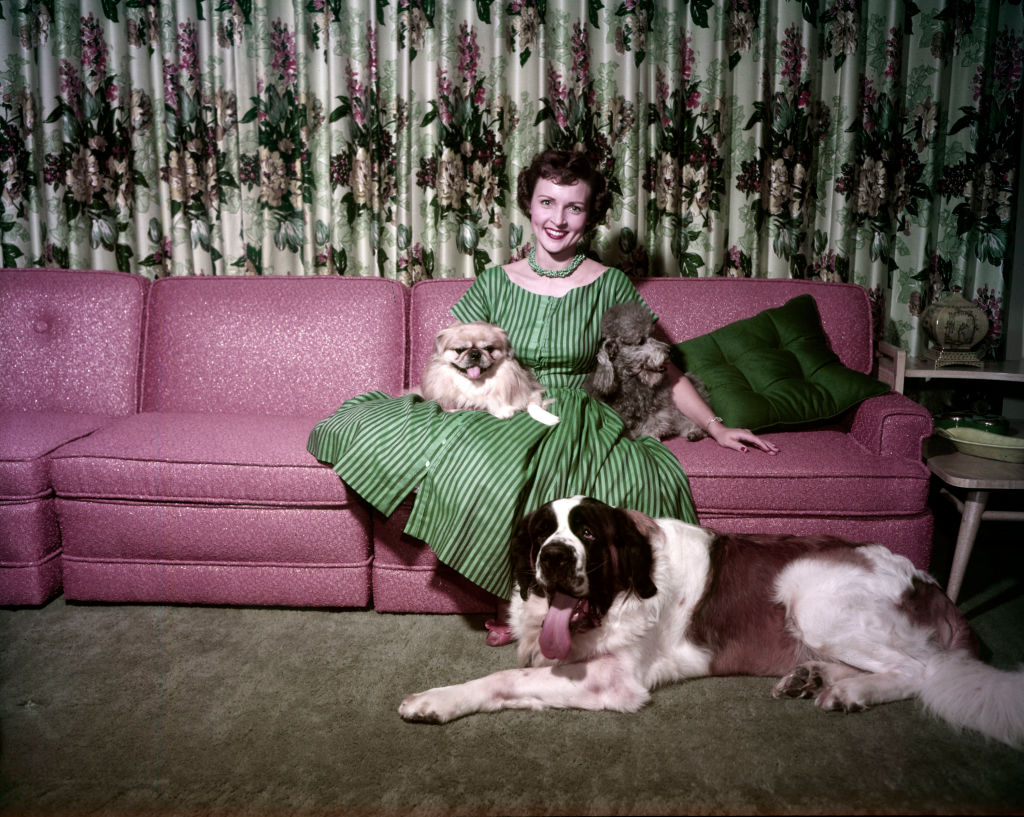 Betty White sits on a couch surrounded by three dogs
