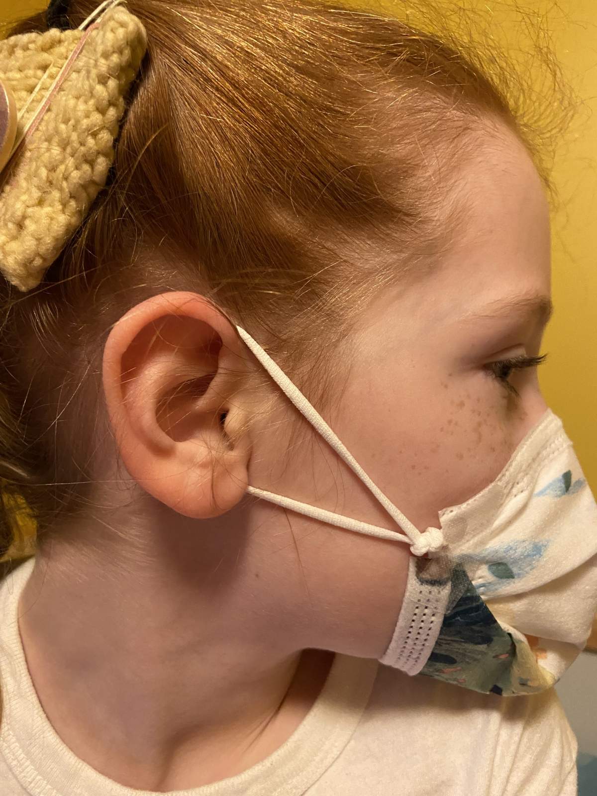 Sarah Mackey’s eight-year-old daughter wearing the mask she was supplied at school with her “knot and tuck” modification.