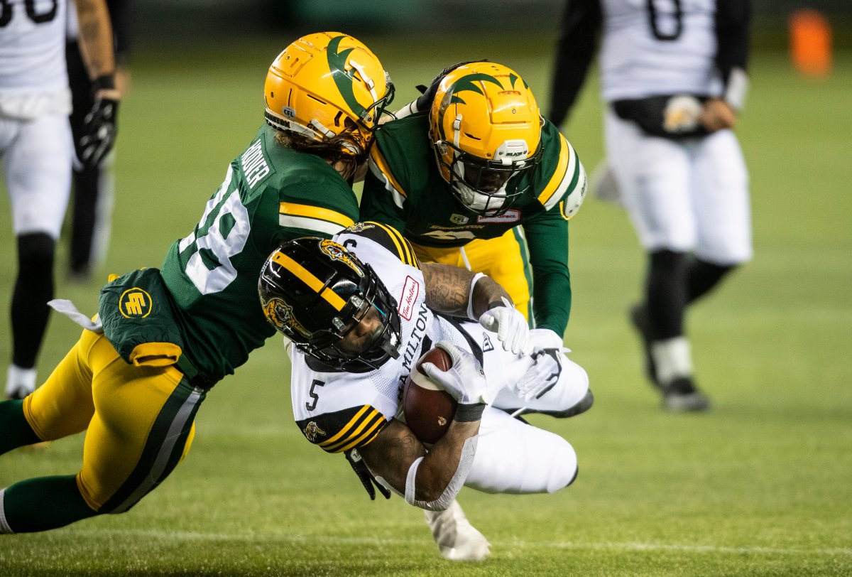Hamilton Tiger-Cats' Don Jackson (5) is tackled by Edmonton Elks' Jordan Hoover (28) and Trumaine Washington (8) during first half CFL action in Edmonton, Alta., on Friday October 29, 2021. 