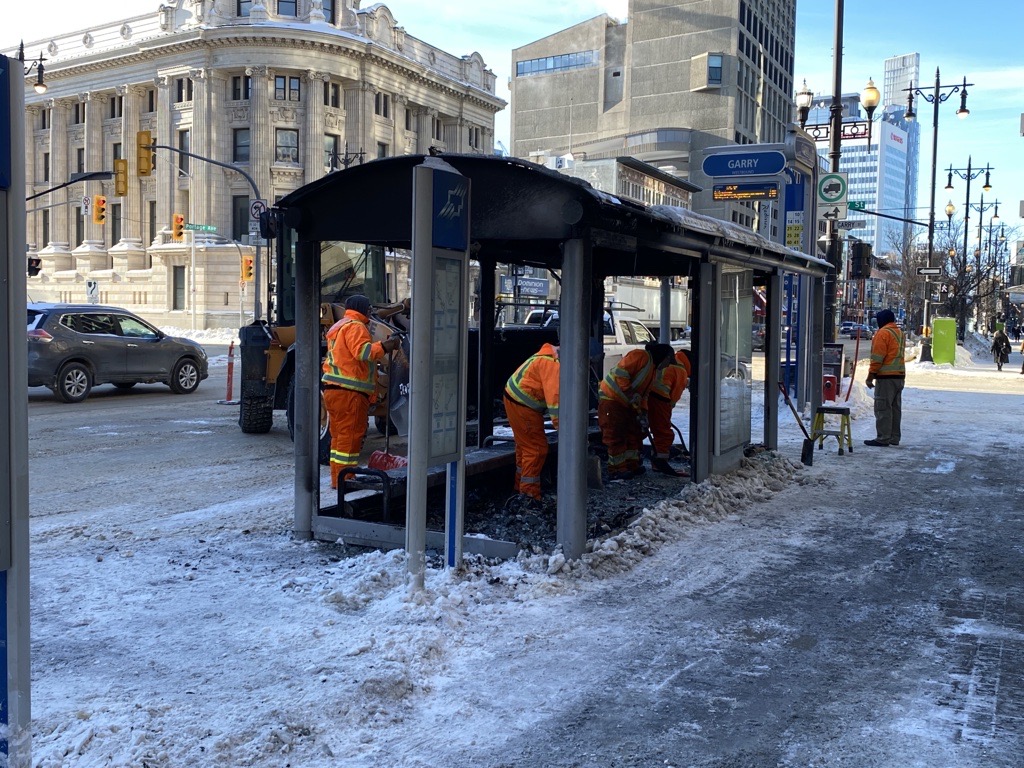 Cleanup underway at a burned-out bus shelter in downtown Winnipeg.