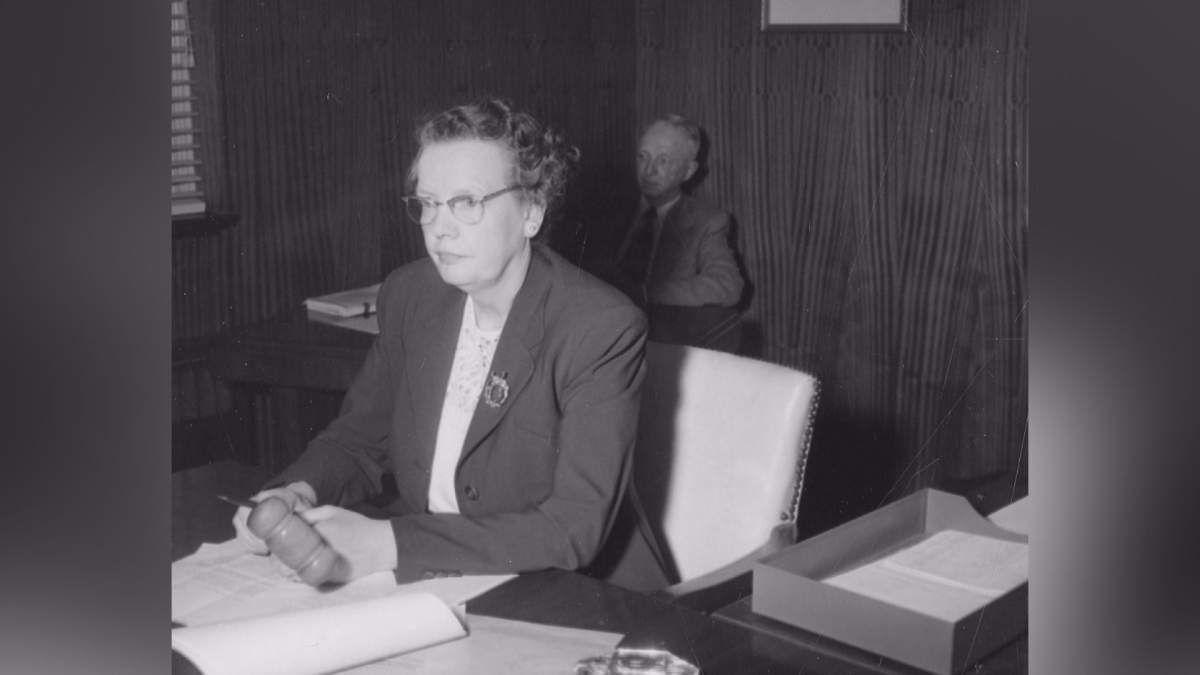 Photograph of Deputy Mayor of the City of Lethbridge, Lillian Parry, officiating at a meeting of City Council. In the background, H. W. Menzie, City Solicitor. Taken May 4, 1953.