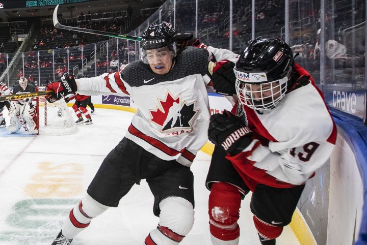 Canada's Carson Lambos (4) checks Austria's Marco Kasper (19) during third period IIHF World Junior Hockey Championship action in Edmonton on Tuesday, December 28, 2021. 