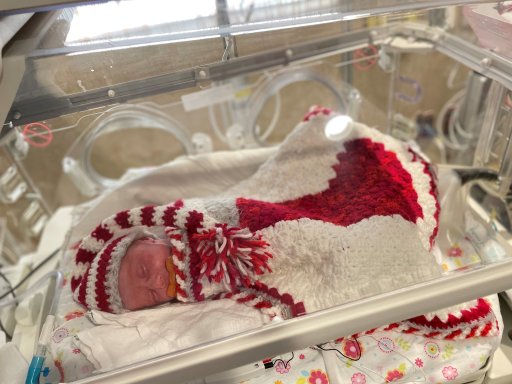 A baby wearing a crochet outfit in the NICU.
