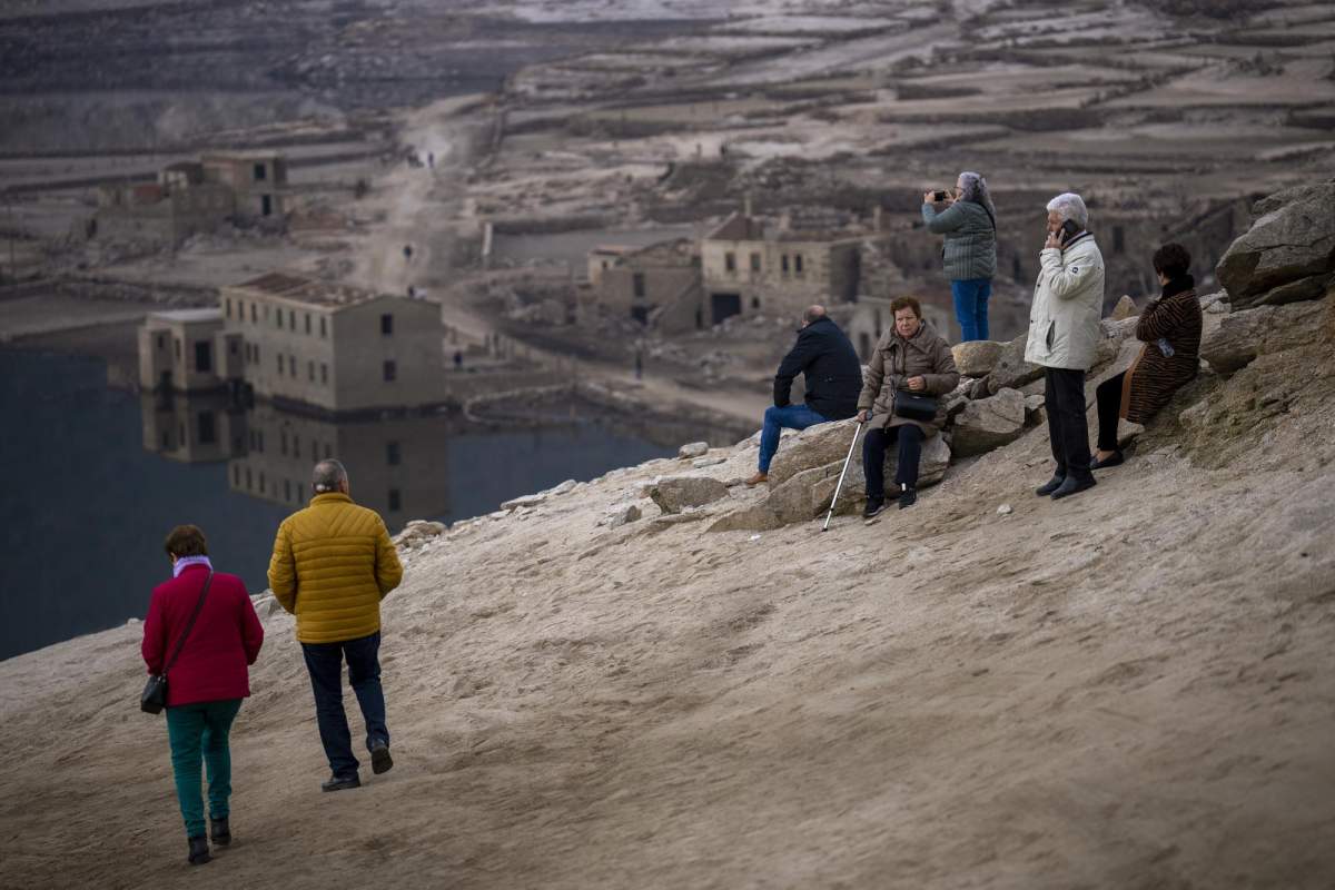 Visitors look at the old village of Aceredo emerged due to drought at the Lindoso reservoir, in northwestern Spain, Saturday, Feb. 12, 2022