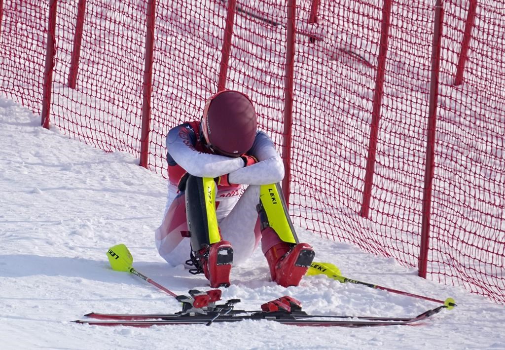 Mikaela Shiffrin, of the United States sits on the side of the course after skiing out in the first run of the women's slalom at the 2022 Winter Olympics, Wednesday, Feb. 9, 2022, in the Yanqing district of Beijing. (AP Photo/Robert F. Bukaty).