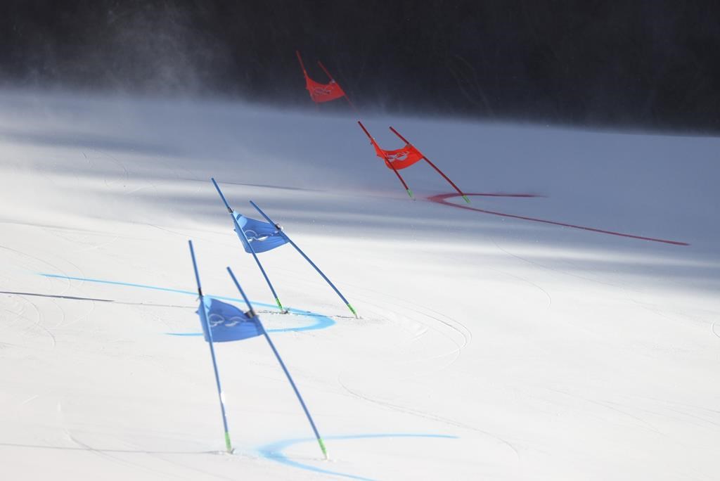 Gate flags bend in the wind after high winds caused a delay in the start of the mixed team parallel skiing event at the 2022 Winter Olympics, Saturday, Feb. 19, 2022, in the Yanqing district of Beijing. (AP Photo/Alessandro Trovati).