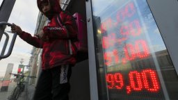 A food delivery man leaves an exchange office with screen showing the currency exchange rates of U.S. Dollar and Euro to Russian Rubles in Moscow, Russia,.