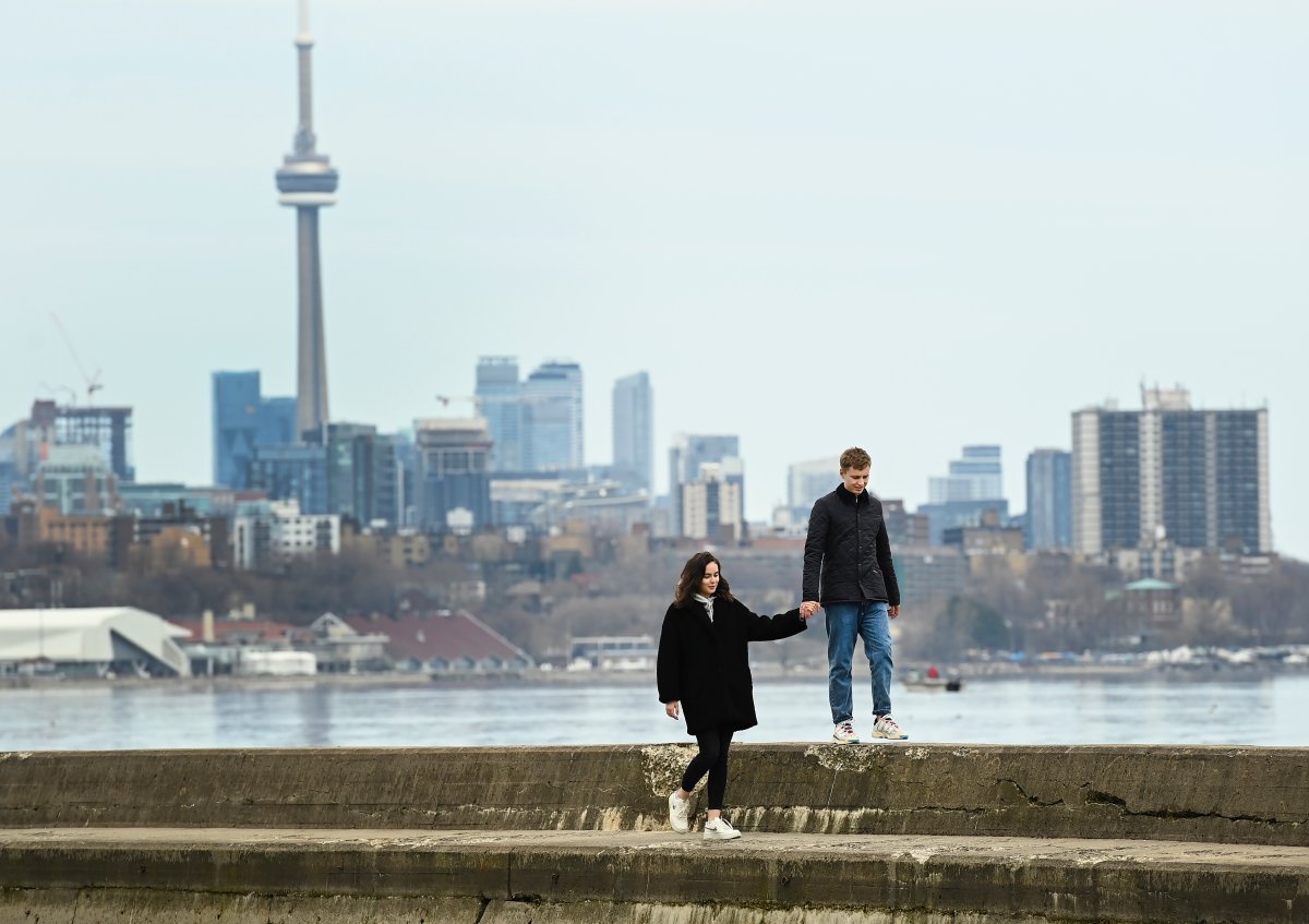 People hold hands over looking the city skyline on Lake Ontario near Humber Bay during the COVID-19 pandemic in Toronto on Monday, April 5, 2021.