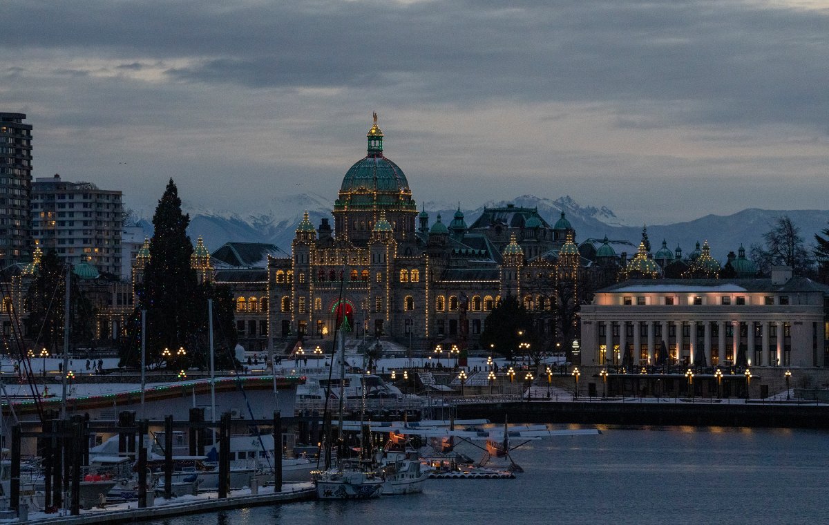Snow capped mountains are seen behind a lit up British Columbia Legislature in downtown Victoria, Wed. Dec. 29, 2021.