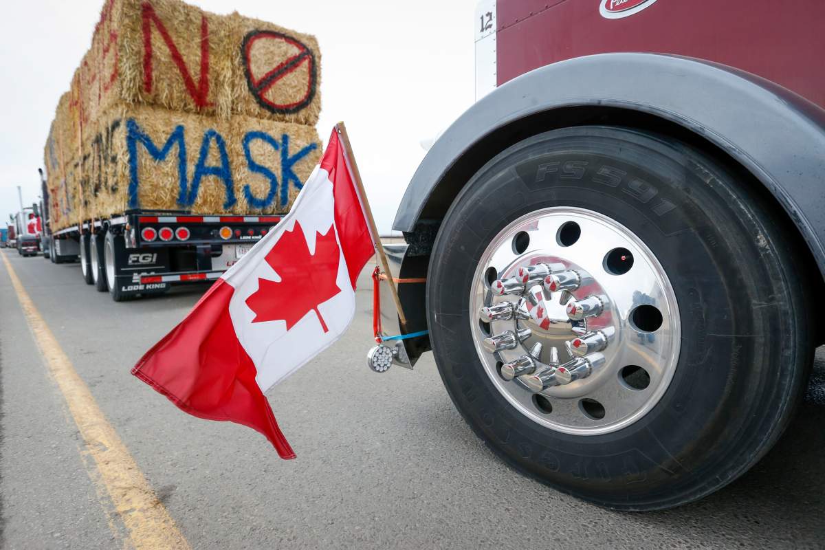 The Canadian flag is reflected in a wheel hub as anti-mandate demonstrators gather as a truck convoy blocks the highway the busy U.S. border crossing in Coutts, Alta., Monday, Jan. 31, 2022.