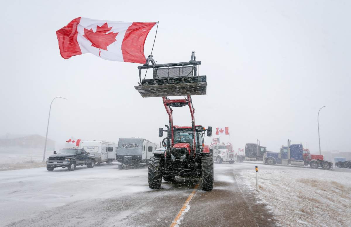 Anti-mandate demonstrators gather as a truck convoy blocks the highway the busy U.S. border crossing in Coutts, Alta., Monday, Jan. 31, 2022.