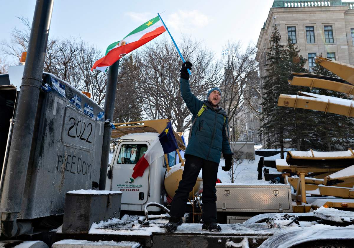 A demonstrator screams for liberty while standing on a truck parked by the legislature in protest against COVID-19 restrictions, in Quebec City, Saturday, Feb. 5, 2022.