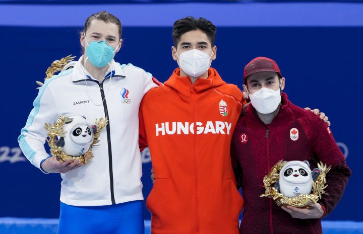 Men’s 500 metre short-track speed skating gold medallist Shaoang Liu of Hungary is flanked by silver medallist Konstantin Ivliev of the Russian Olympic Committee and bronze medallist Steven Dubois on the podium at the Olympic Winter Games in Beijing, Sunday, Feb. 13, 2022.