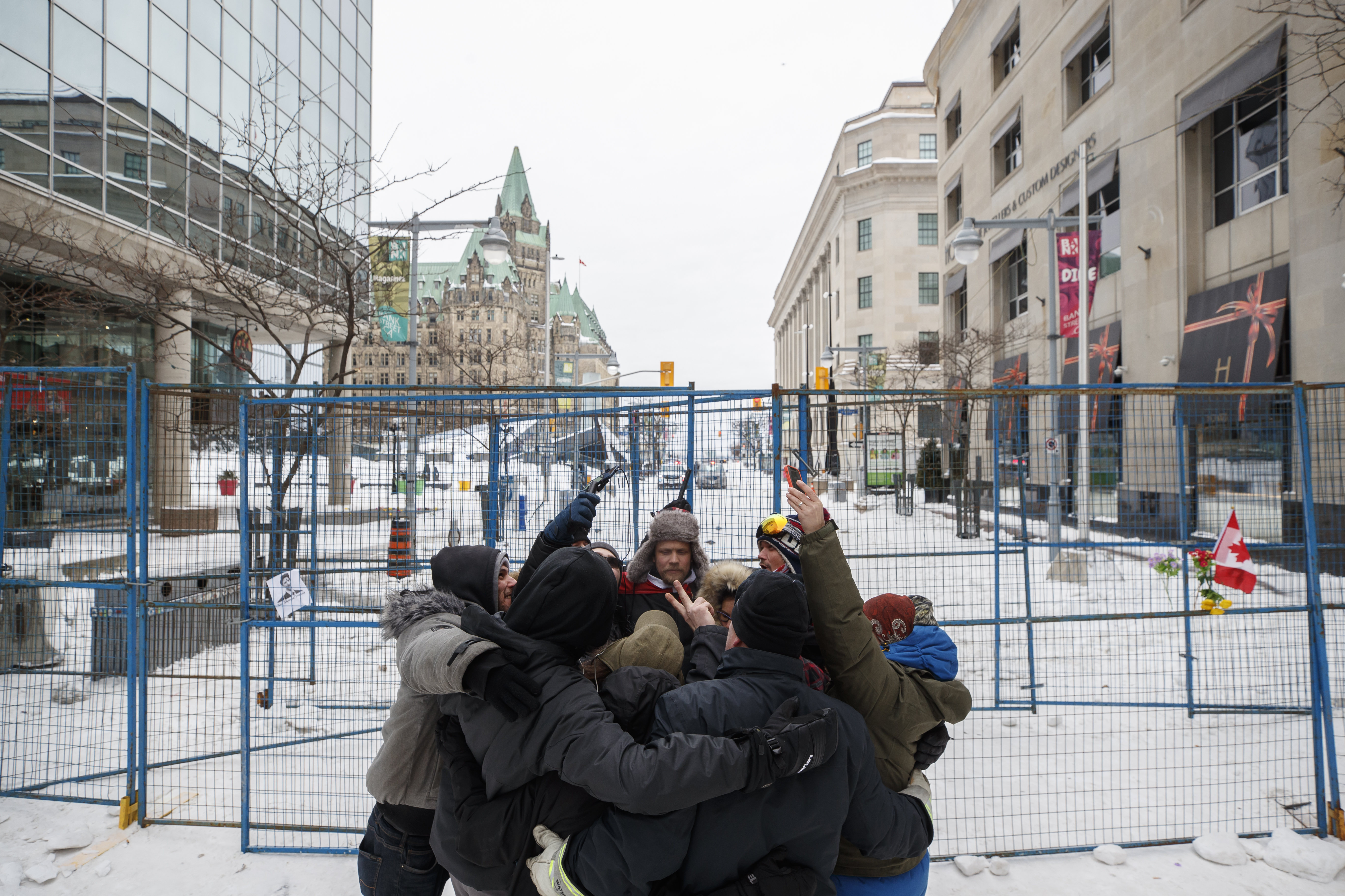 People hug outside of a fenced off portion of downtown Ottawa on Sunday, Feb. 20, 2022, after police worked to clear a trucker protest that was aimed at COVID-19 measures that grew into a broader anti-government protest.