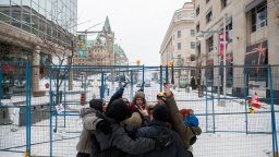 People hug outside of a fenced off portion of downtown Ottawa on Sunday, Feb. 20, 2022, after police worked to clear a trucker protest that was aimed at COVID-19 measures that grew into a broader anti-government protest.