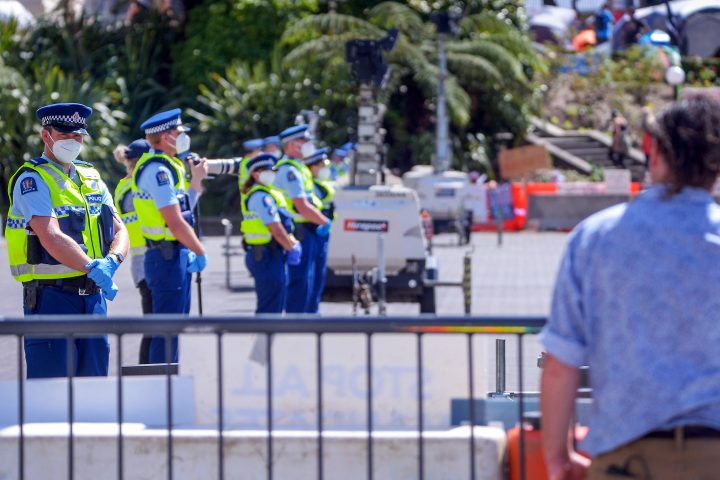 Police offices stand guard in front of the parliament as anti-vaccine demonstrators occupy the grounds nearby in Wellington on February 22, 2022. 