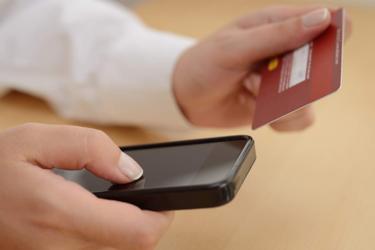 A woman making a purchase with a credit card using a smart phone.