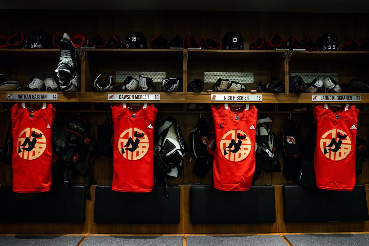 The New Jersey Devils warm-up jerseys hang in the locker room.