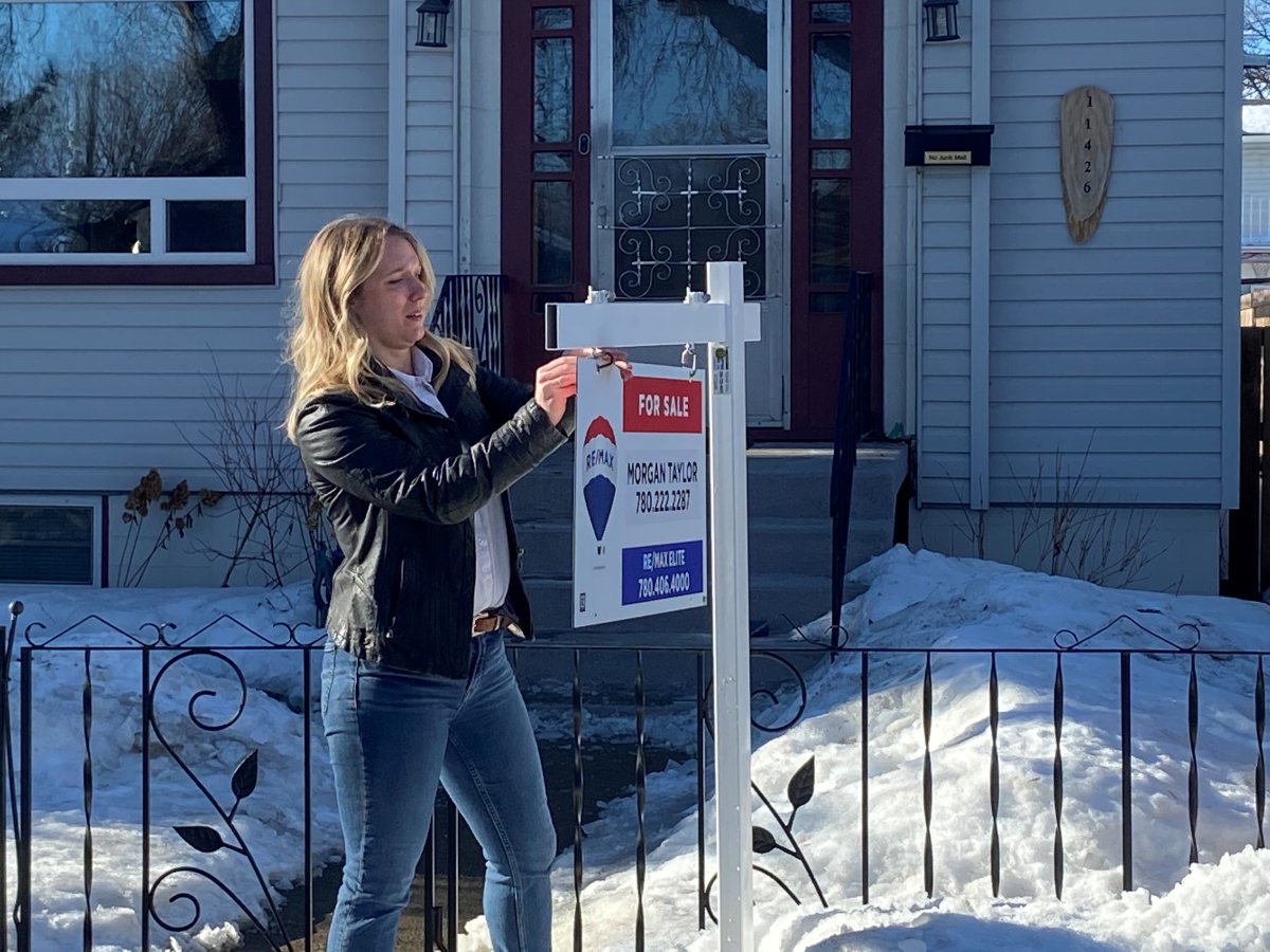 Realtor Morgan Taylor hangs the sign for her newest listing in February 2022. Real estate prices in Edmonton kept falling in November 2022.