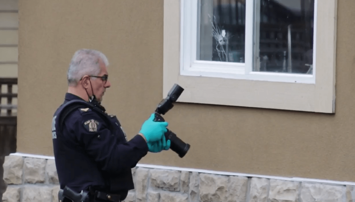 An RCMP officer photographs a bullet hole in the window of a Surrey home. 