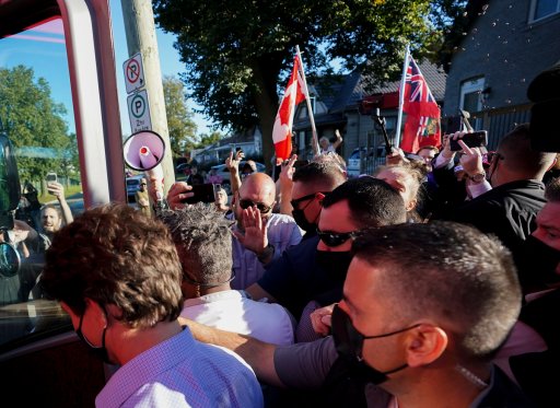 Gravel is thrown, top right, at Liberal leader Justin Trudeau, left, as the RCMP security detail provide protection, while protesters shout at a local microbrewery during the Canadian federal election campaign in London Ont., on Monday, September 6, 2021.