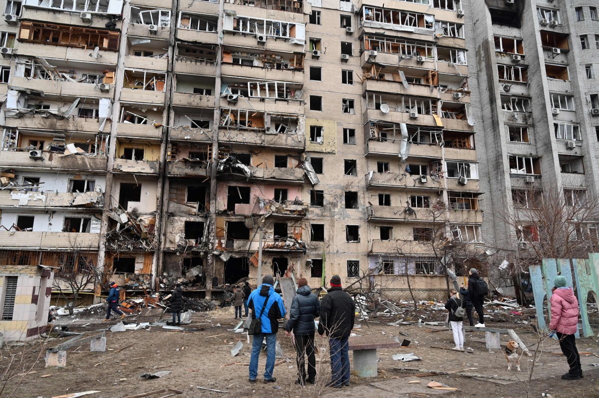 People look at a damaged residential building at Koshytsa Street, a suburb of the Ukrainian capital Kyiv, where a military shell allegedly hit, on February 25, 2022.