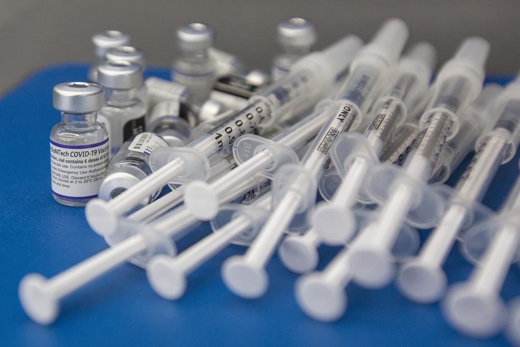 Syringes and vials of Pfizer-BioNTech COVID-19 vaccine are seen on a work surface in Kingston, Ont., Saturday, Dec. 18, 2021.