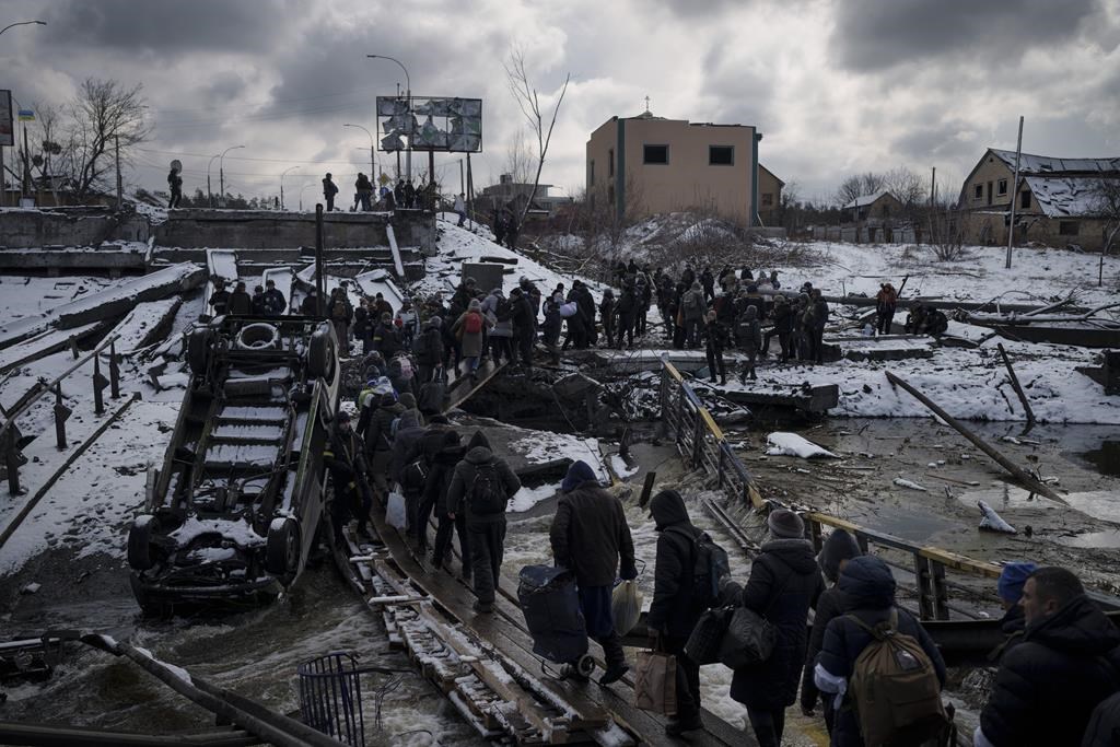 Ukrainians cross an improvised path under a destroyed bridge while fleeing Irpin. (AP Photo/Felipe Dana)