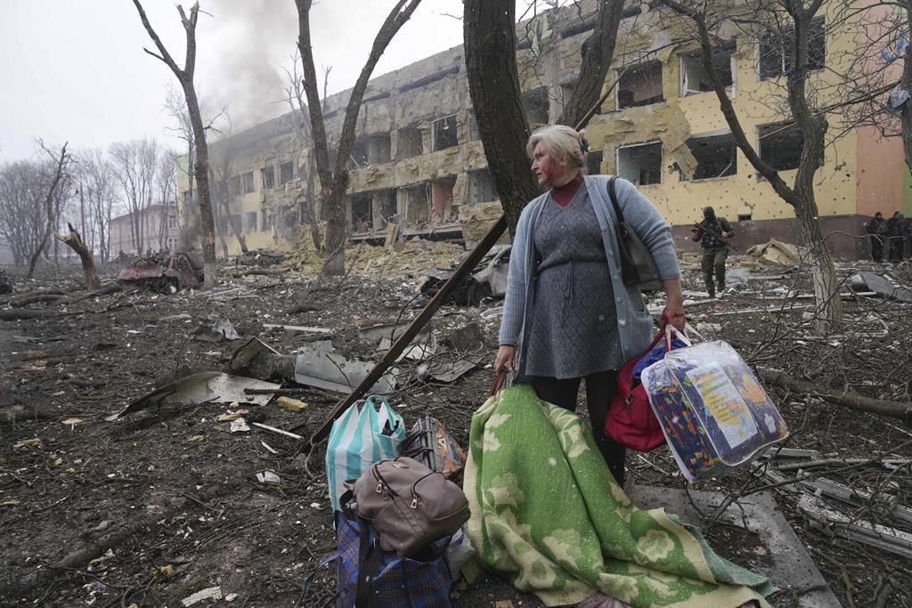 A woman walks outside the damaged by shelling maternity hospital in Mariupol, Ukraine, Wednesday, March 9, 2022.