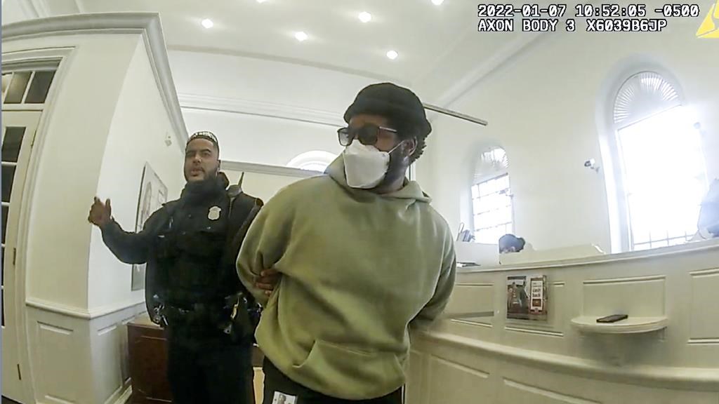 A screencapture shows Ryan Coogler being handcuffed in front of a bank teller's station.