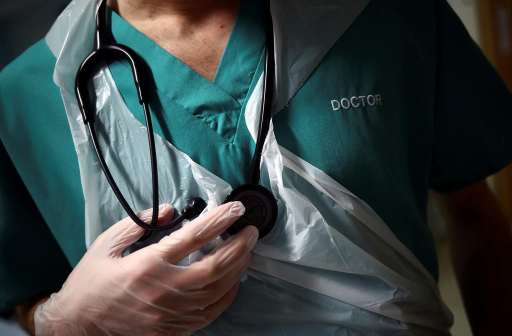 A junior doctor holds his stethoscope during a patient visit at the Royal Blackburn Teaching Hospital, in Blackburn, England, Thursday, May 14, 2020.