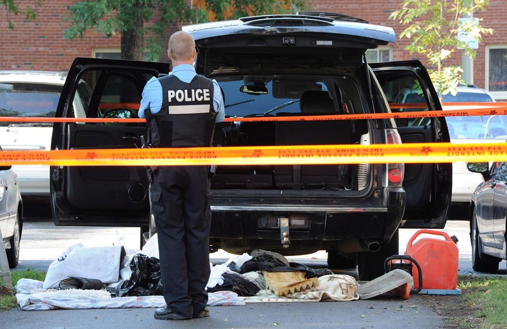 A police officer looks towards a black SUV that has had its contents removed at a crime scene outside the Metropolis in Montreal on Wednesday, Sept. 5, 2012. 