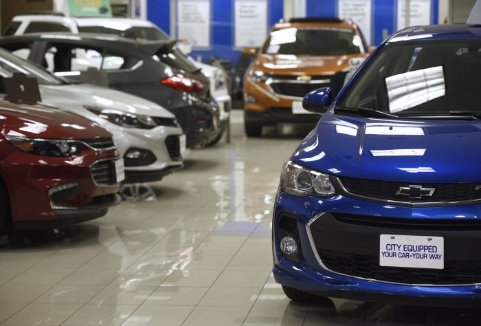 Cars and trucks on the lot and in a showroom .