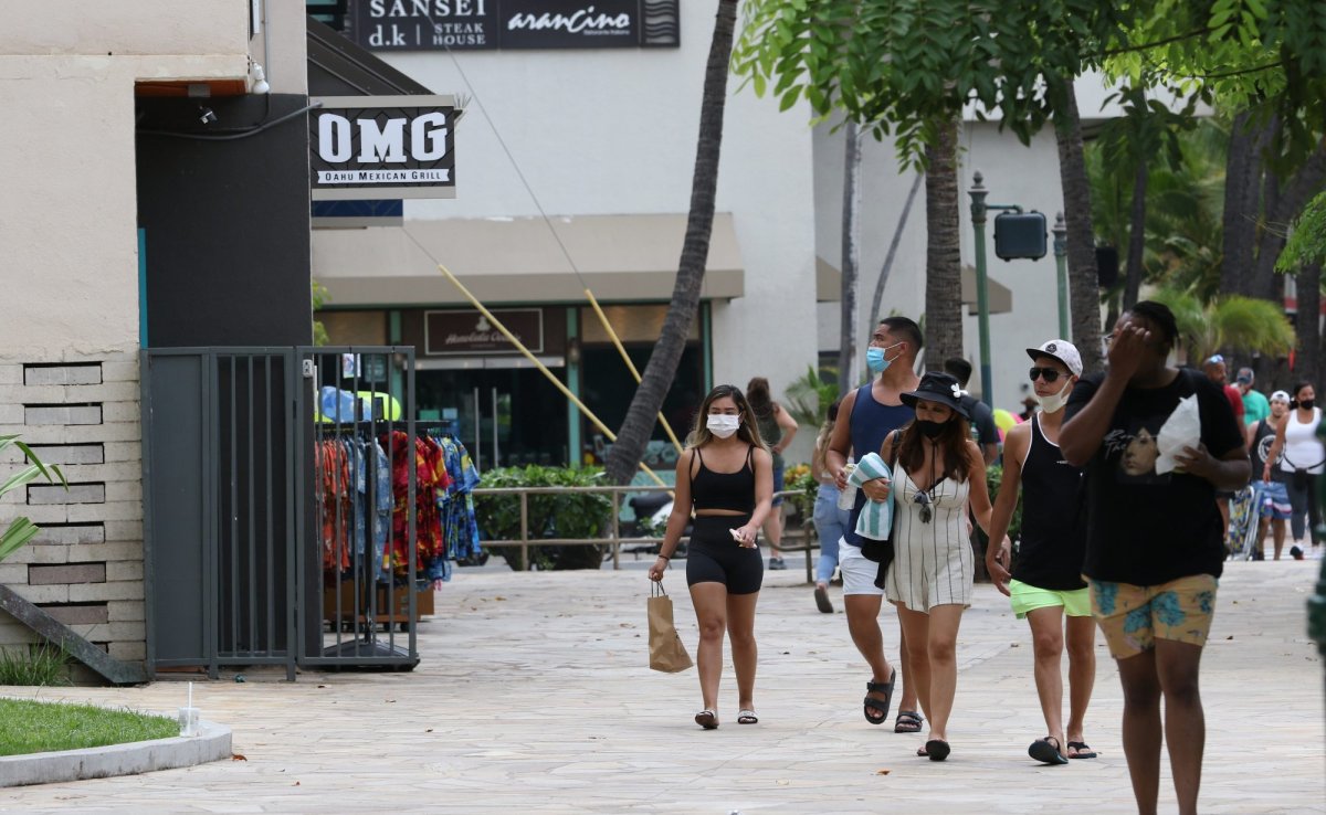 FILE - In this Aug. 24, 2021 file photo people walk past Waikiki restaurants and shops in Honolulu. The mayor of Honolulu says starting Sept. 13 the city will require patrons of restaurants, bars, museums, theaters and other establishments to show proof of vaccination or a recent negative test for COVID-19. (AP Photo/Caleb Jones, File).