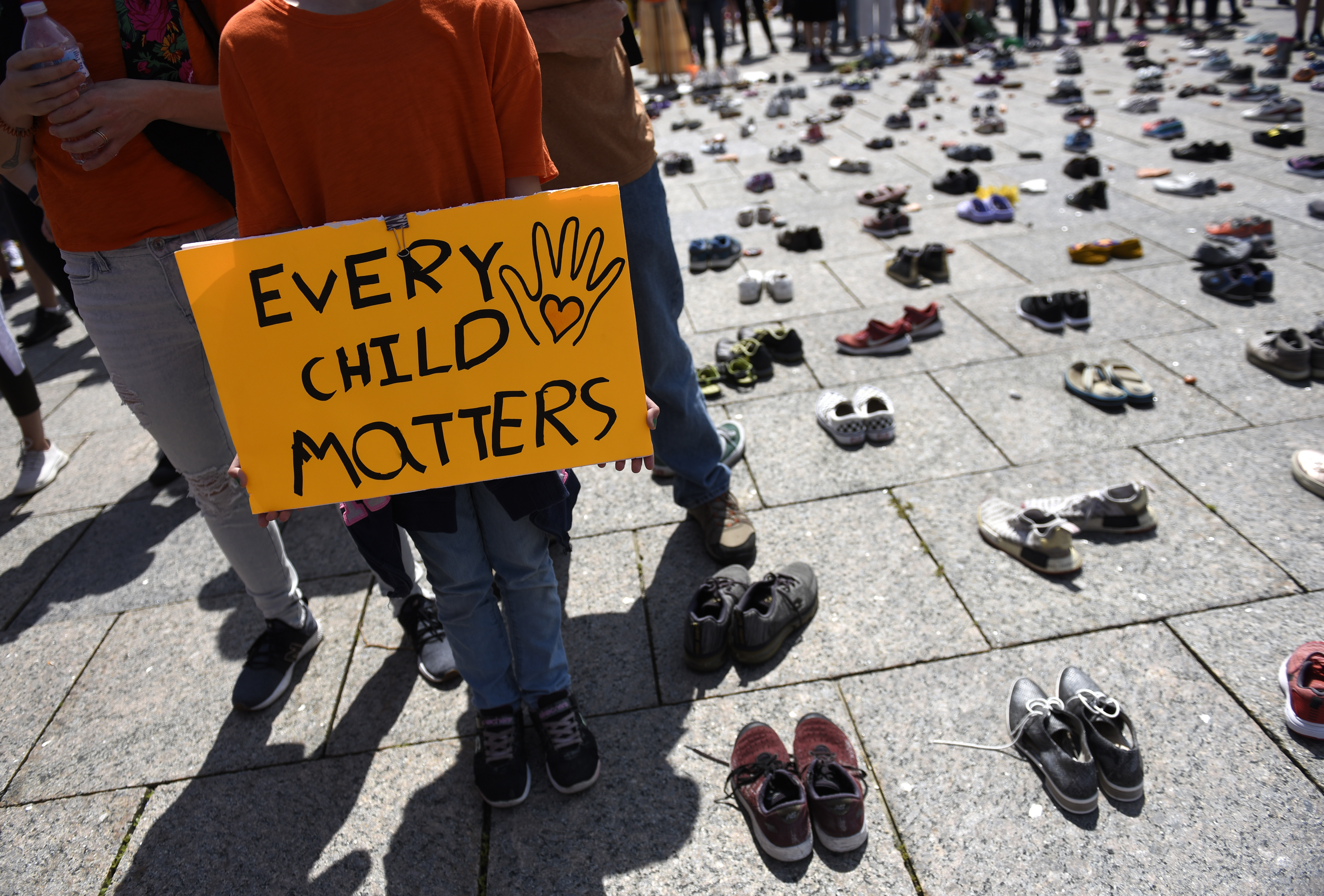 People stand on Parliament Hill alongside a memorial for children who died at Indian Residential Schools, during a rally to demand an independent investigation into Canada's crimes against Indigenous Peoples, in Ottawa on Saturday, July 31, 2021.