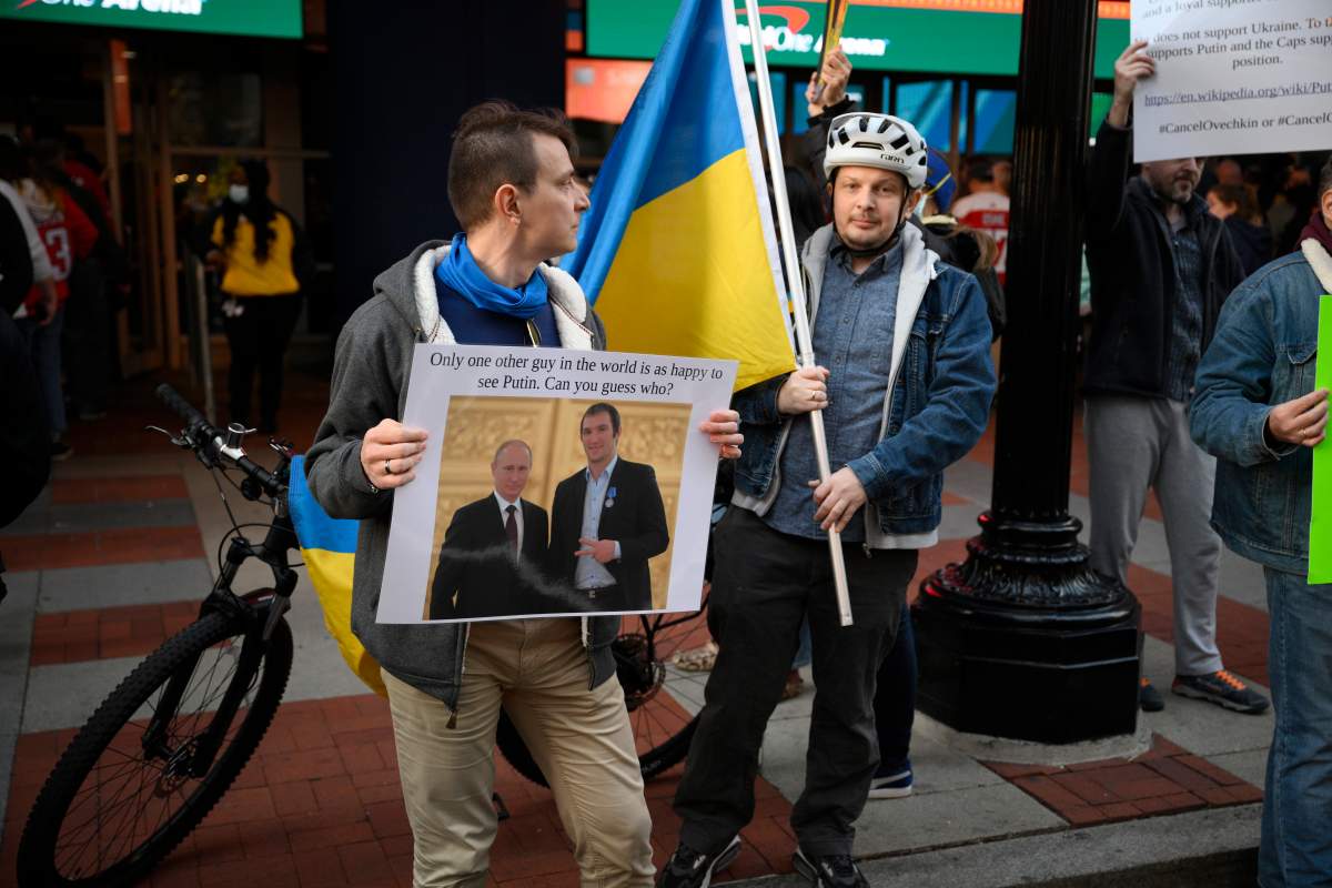 Demonstrators display a picture showing Vladimir Putin and Washington Capitals' Alex Ovechkin as well as Ukrainian flags outside of the entrance of Capital One Arena before an NHL hockey game between the Washington Capitals and the Seattle Kraken, Saturday, March 5, 2022, in Washington.