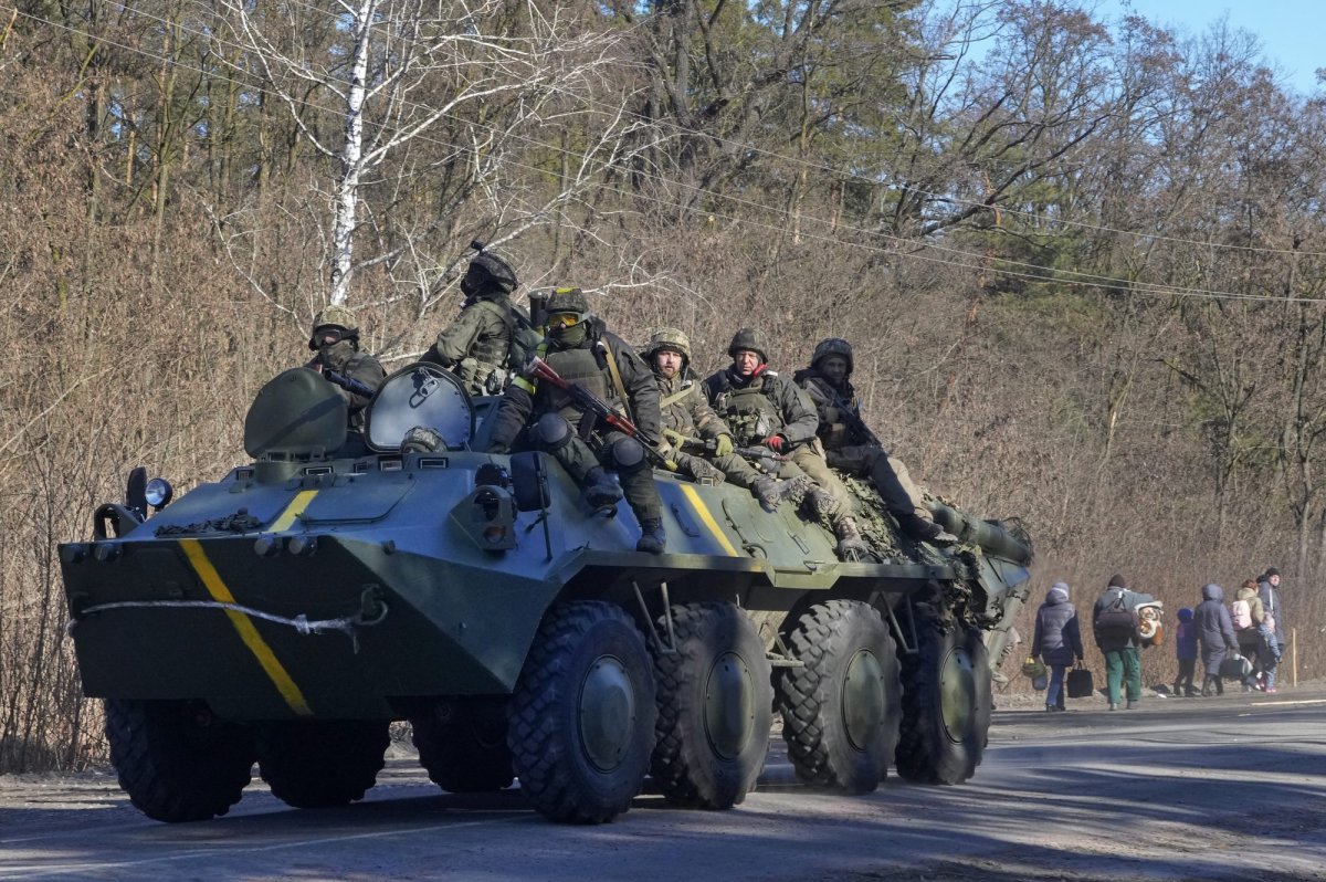 Ukrainian soldiers on an armored personnel carrier pass by people carrying their belongings as they flee the conflict, in the Vyshgorod region close to Kyiv, Ukraine, Thursday, March 10, 2022. 
